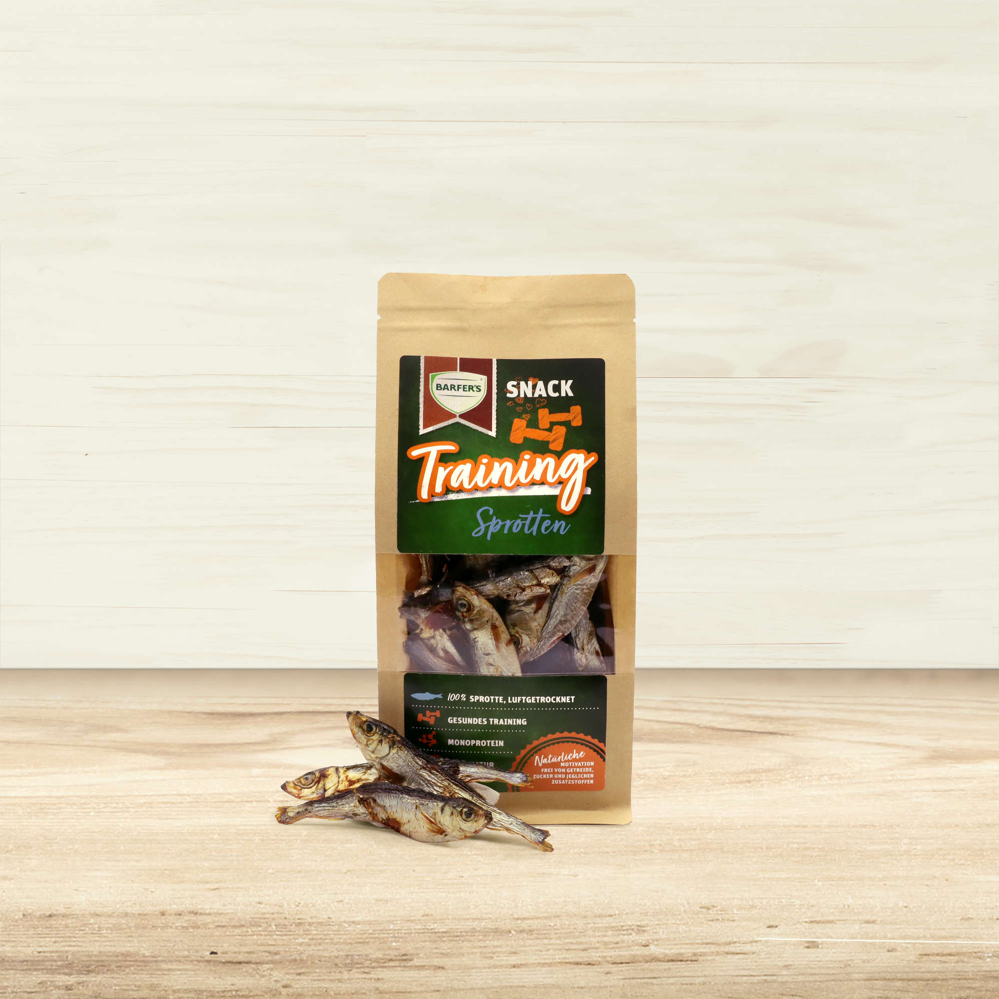 Luftgetrocknete Sprotten der Marke BARFER'S liegen neben einer Verpackung "Trainings Snack Sprotten“.