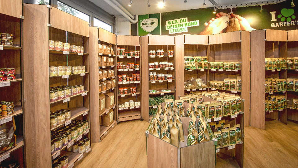 10 braune Holzregale auf der Verkaufsfläche im BARFER'S Store in Berlin-Marienfelde. Sie sind gefüllt mit BARF-Zusätzen und Leckerli für Hunde und Katzen.