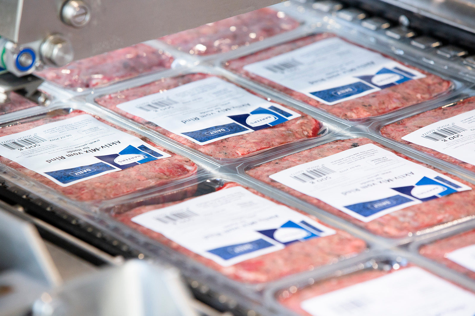 Frisch verpackte BARFER’S Aktiv-Mix Rind Fleischpackungen auf einem Förderband in der Produktion