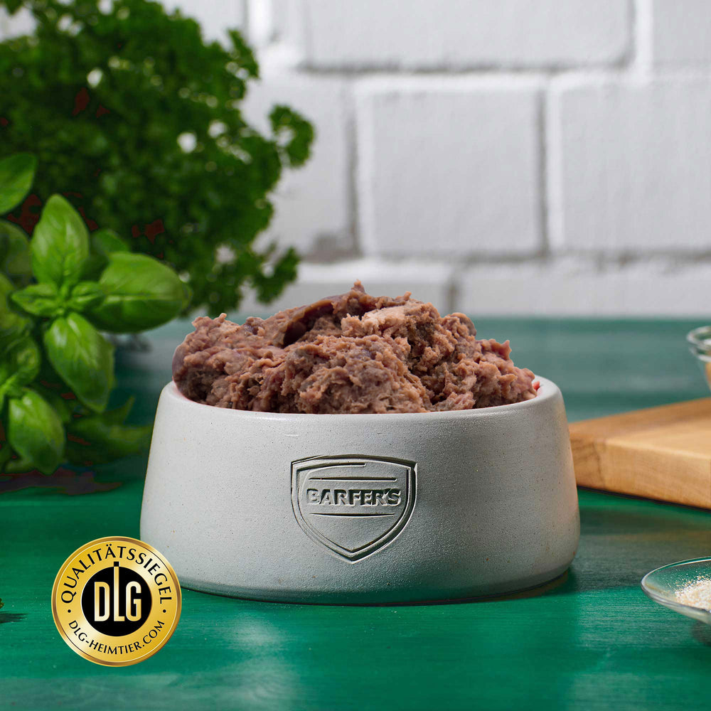 Vollwertiges Fertigbarf für Katzen im BARFER’S Napf – der Komplett-Mix Lamm mit DLG-Siegel servierbereit angerichtet, im Hintergrund frische Kräuter