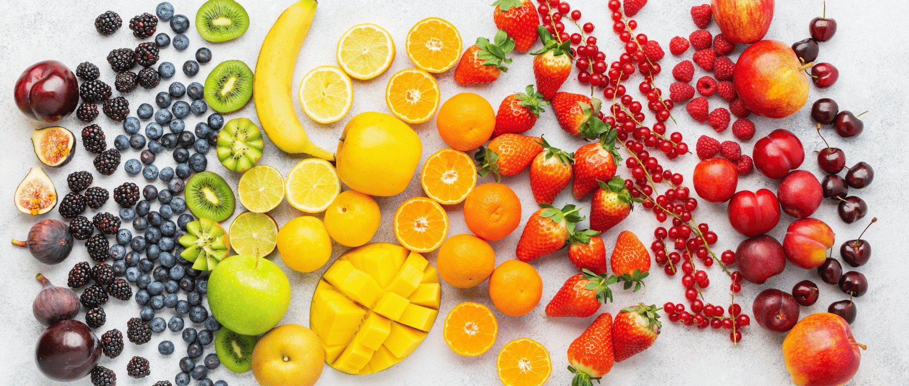 Frisches Obst sortiert nach Regenbogenfarben: Pflaumen, Feigen, Brombeeren, Blaubeeren, Kiwis, Limetten, Zitronen, Mango, Mandarinen, Erdbeeren, Johannisbeeren, Himbeeren, Nektarinen, Äpfel und Kirschen