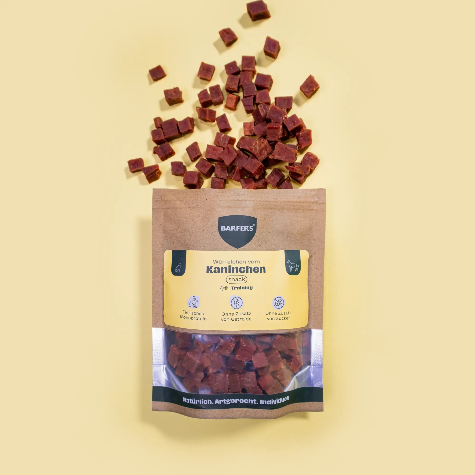 Luftgetrocknete Kaninchen-Leckerli in Würfelform der Marke BARFER'S liegen oberhalb einer geöffneten Verpackung "Würfelchen vom Kaninchen“