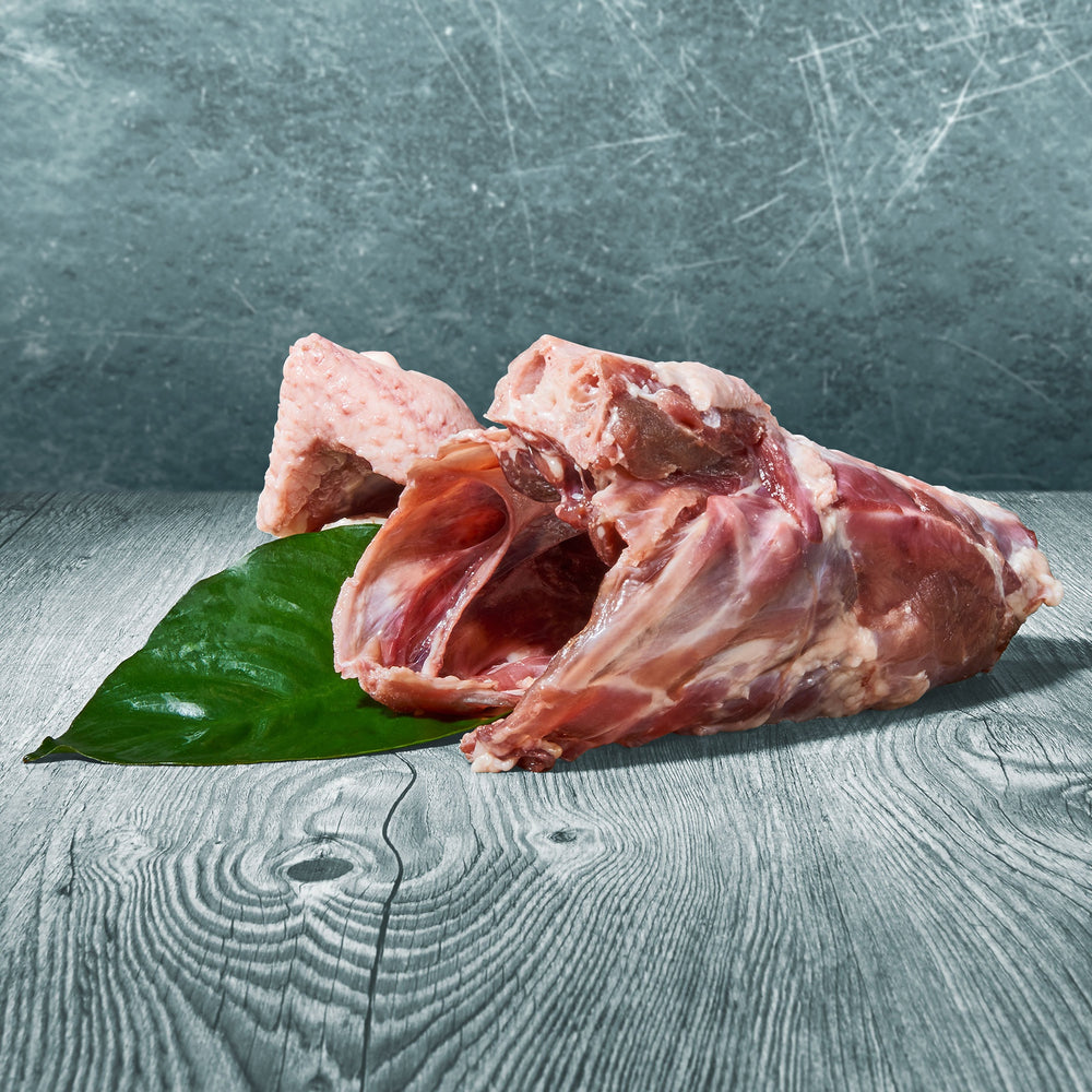 Rohe Entenkarkasse auf einer Holzoberfläche mit grünem Blatt als Dekoration