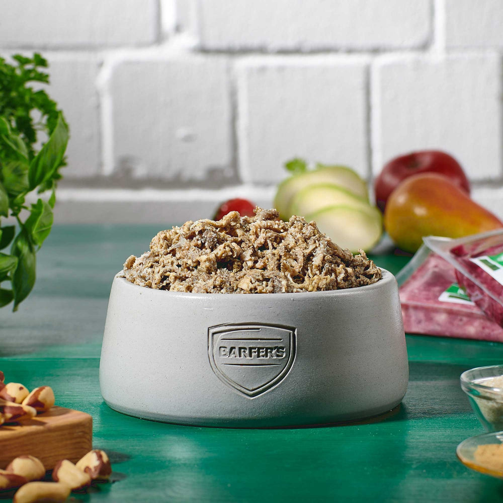 Napf mit gewolftem Rinder-Blättermagen von BARFER’S, dekoriert mit frischem Gemüse im Hintergrund