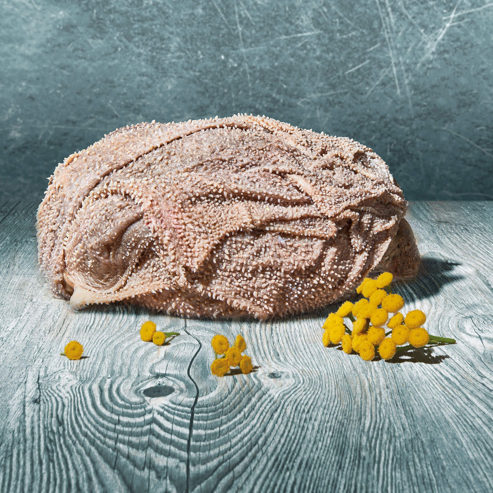 Gefrorener Rinder-Blättermagen im Stück auf Holzoberfläche mit gelben Blüten dekoriert