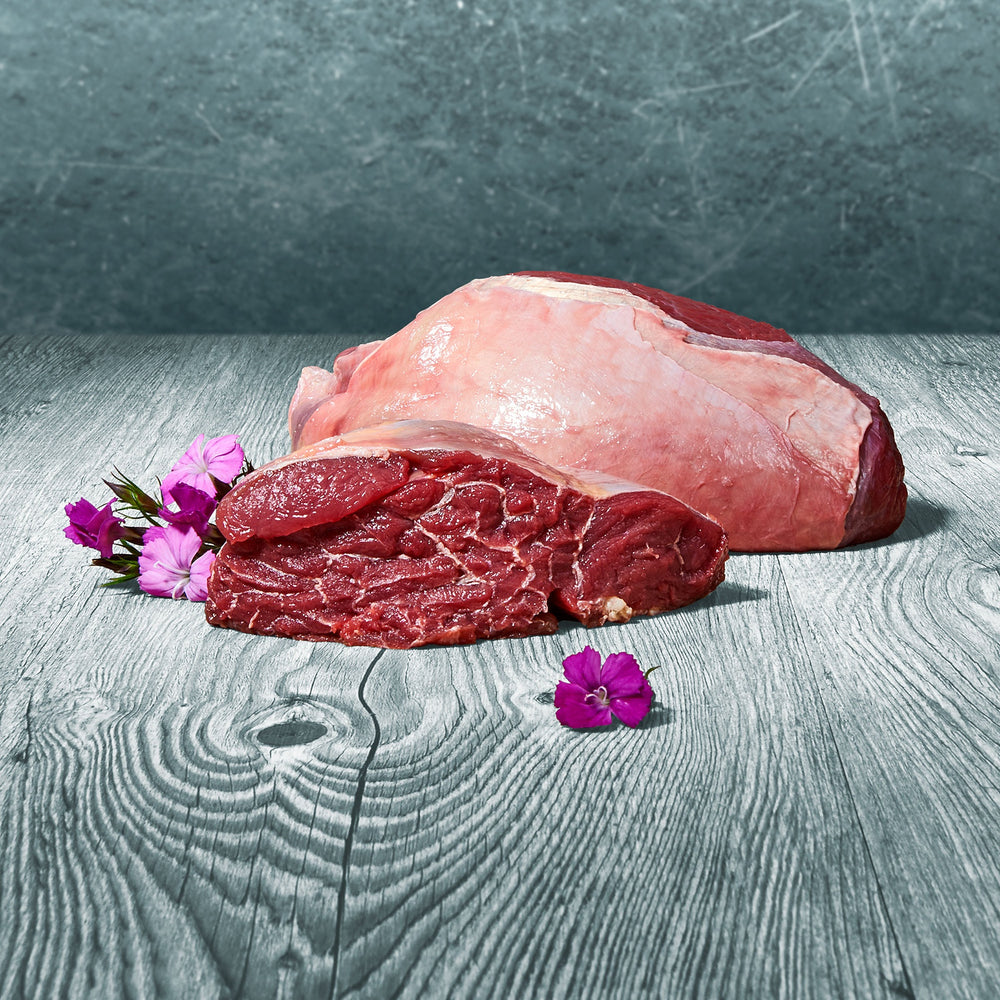 Frisches BARF-Pferdemuskelfleisch im Stück präsentiert auf einer grauen Holzoberfläche