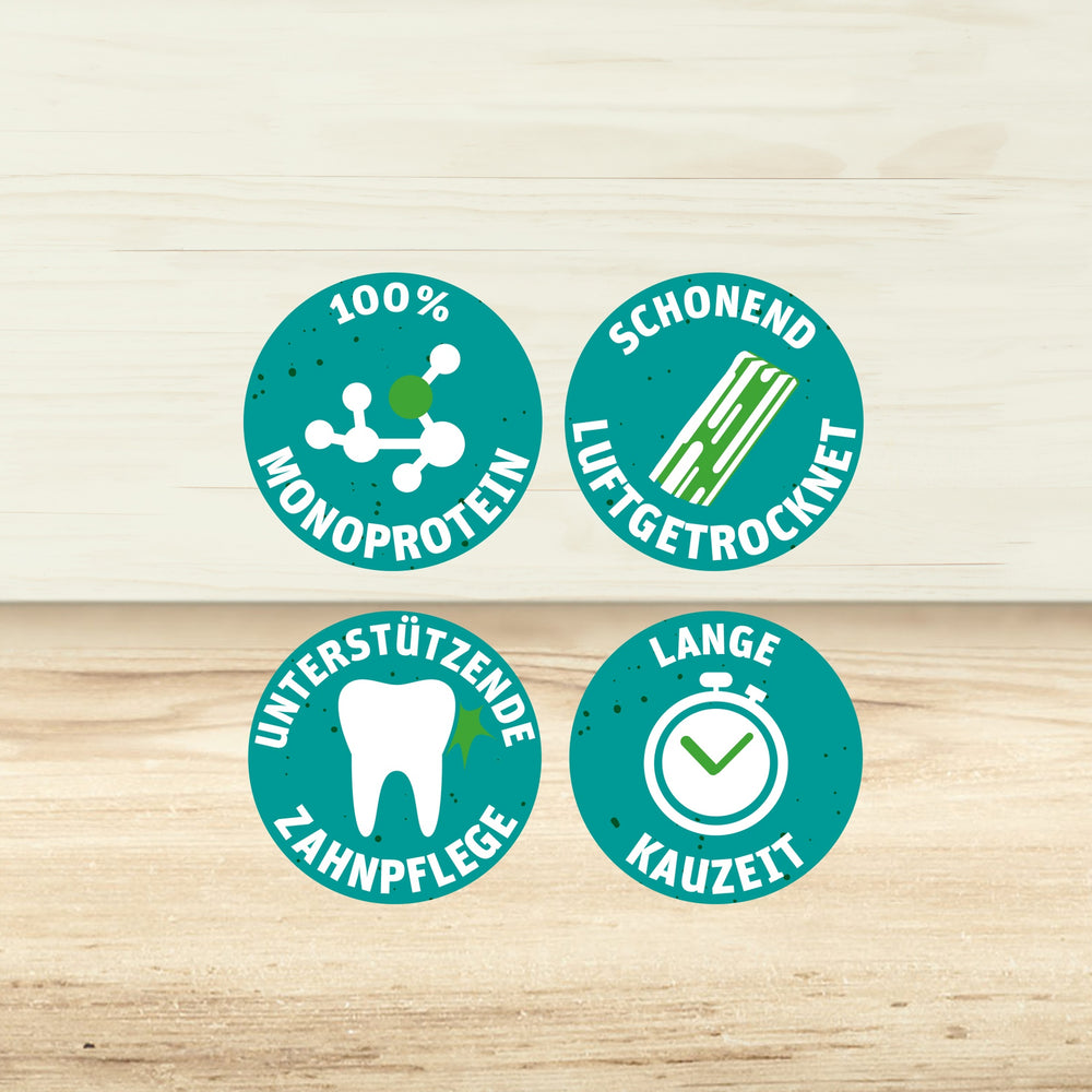 4 Sprechblasen mit den Texten "100% MONOPROTEIN", "SCHONEND LUFTGETROCKNET", "UNTERSTÜTZENDE ZAHNPFLEGE" und "LANGE KAUZEIT“.