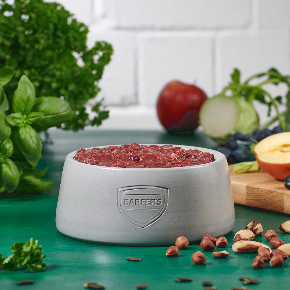 Gefüllter Futternapf mit BARFER’S Innereien-Mix Rind – artgerechtes BARF-Futter für Hunde aus Rinderleber, Rinderniere, Rindermilz und Rinderlunge, dekoriert mit frischem Obst, Gemüse und Nüssen