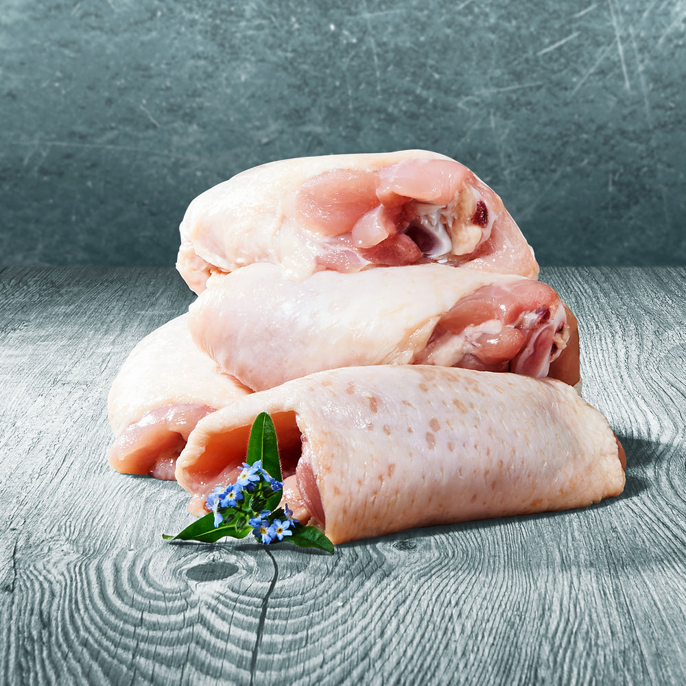 Rohe Hühnerteile zum barfen mit Haut und Knochen auf Holztisch, dekoriert mit einer kleinen Blüte