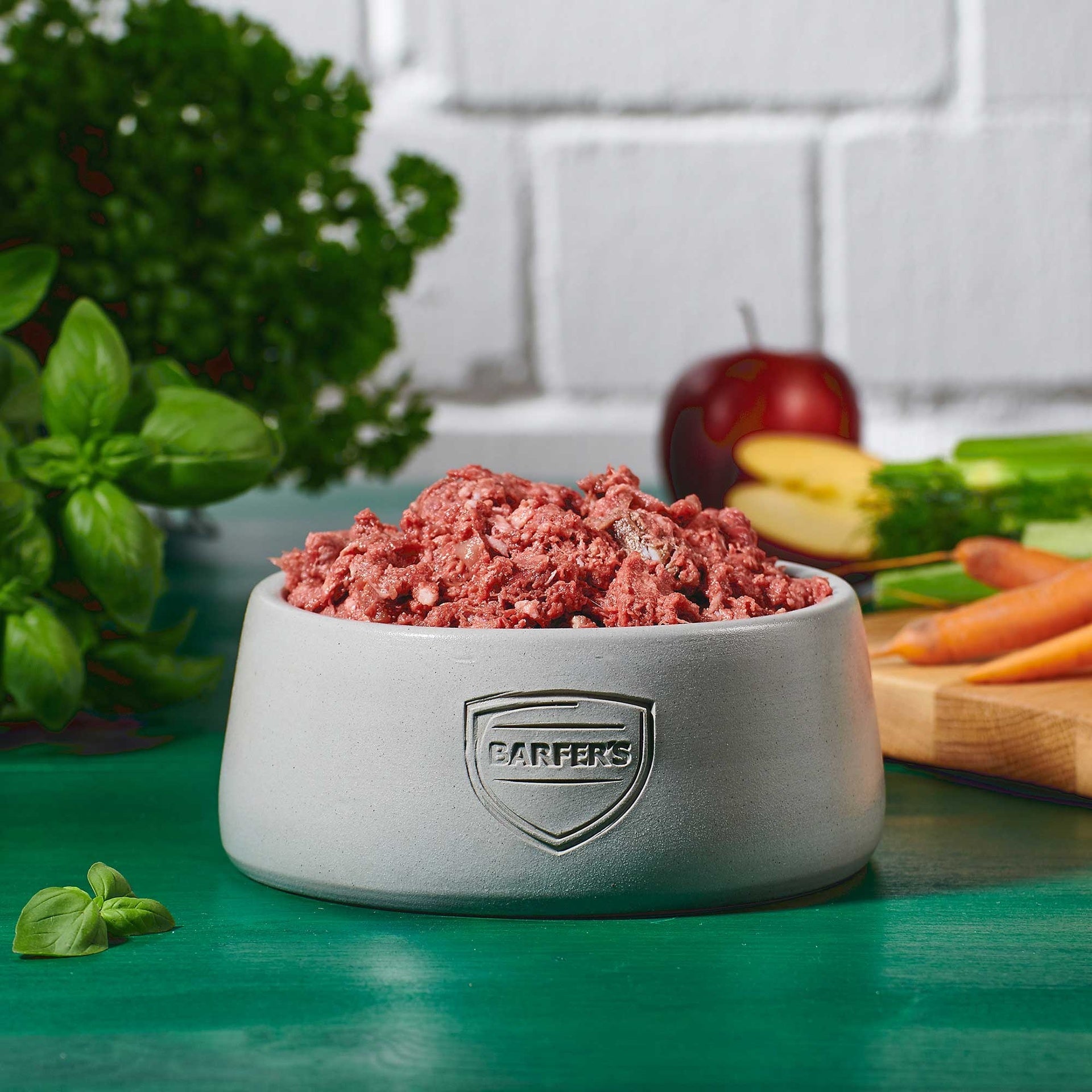 Hellgrauer Keramiknapf mit BARFER’S Logo, gefüllt mit Pur-Mix Pferd – aus Pferdefleisch, Pferdeknochen, Pferdeherz, Pferdemagen, Pferdeleber, Pferdeniere und Pferdelunge, dekoriert mit frischem Gemüse, Apfelhälfte, Möhren, Kräutern und Nüssen