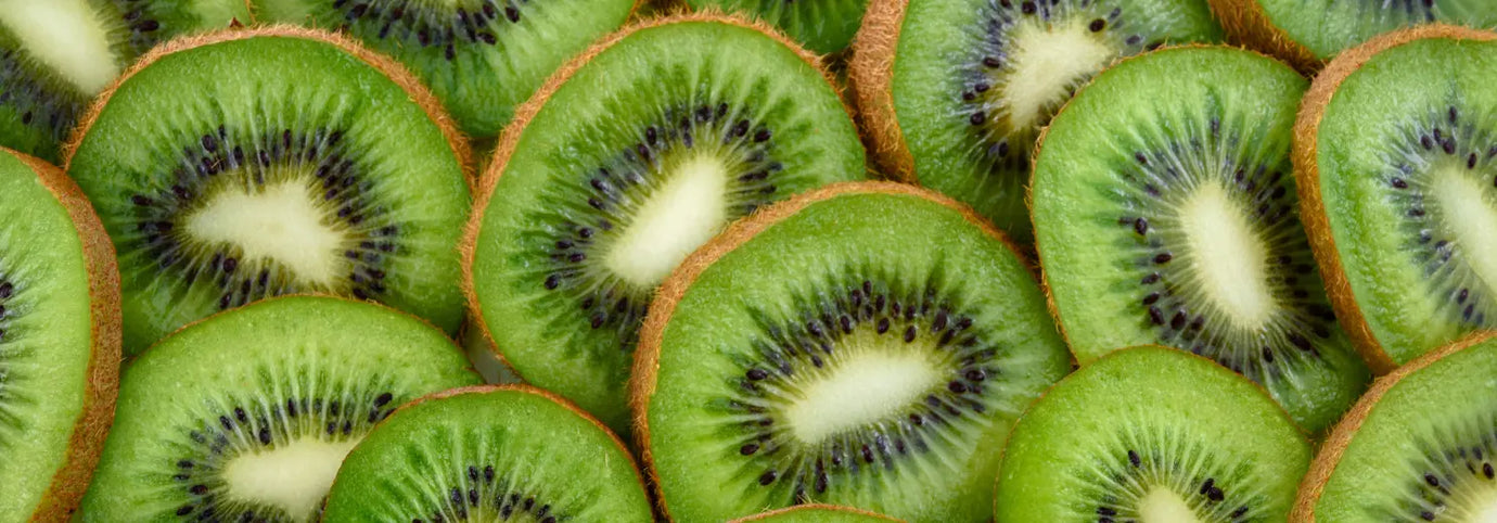 Mehrere aufgeschnittene Kiwis dicht an dicht mit sichtbarem grünem Fruchtfleisch und schwarzen Kernen in Nahaufnahme