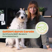 Frau mit zotteligem Hund an einem Holztisch – Text-Overlay: „Geführt durch Carolin – Zertifizierte BARF-Beraterin & Hundebesitzerin" – Siegel: „Zertifizierter BARF-Berater für Hunde & Katzen"