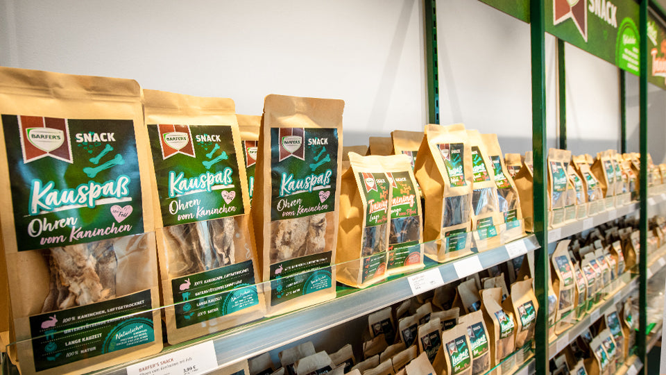 Getrocknete BARF-Leckerli für Hunde und Katzen im Snack-Regal vom BARFER'S Store Berlin-Spandau. Ohren vom Kaninchen und Rinderlunge stehen im Vordergrund.