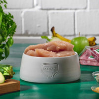 Hähncheninnenfilet im Ganzen im grauen BARFER’S Napf – frisches BARF-Muskelfleisch für Hunde und Katzen mit Zutaten im Hintergrund