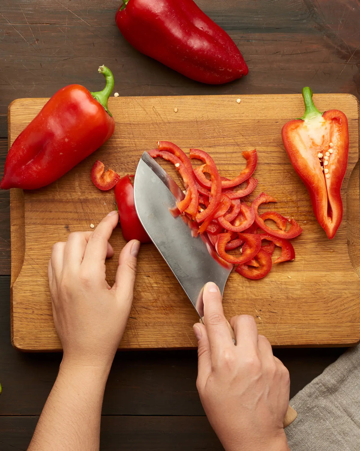 Rote Paprika wird auf einem Schneidebrett in Streifen geschnitten