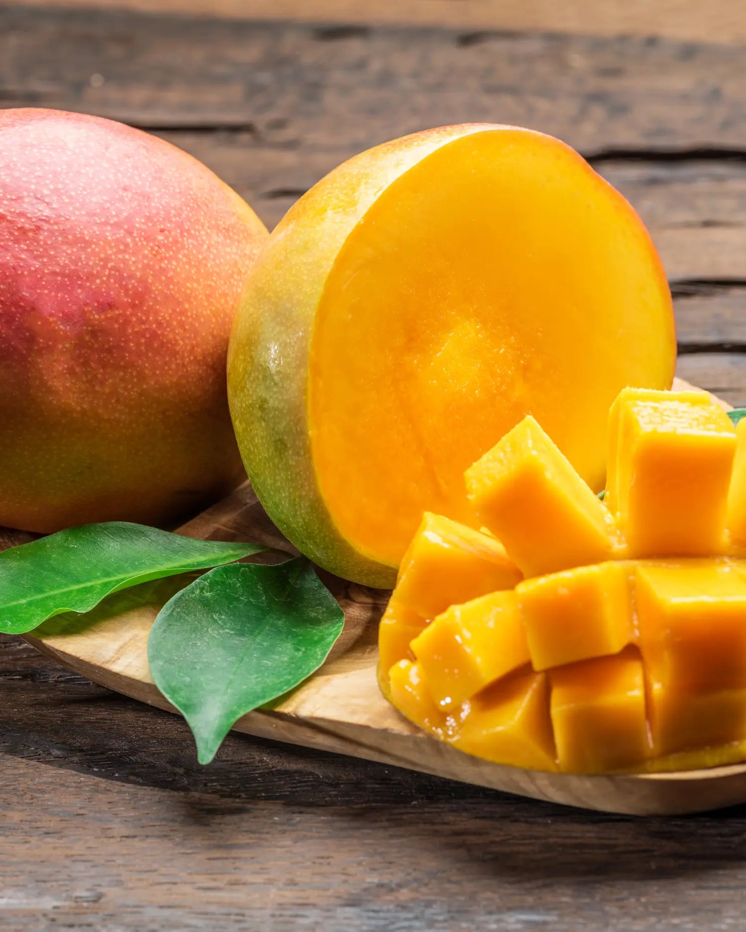 Reife, aufgeschnittene Mango mit gewürfeltem Fruchtfleisch auf einem Holzbrett – als gelegentlicher Obstsnack für Hunde geeignet