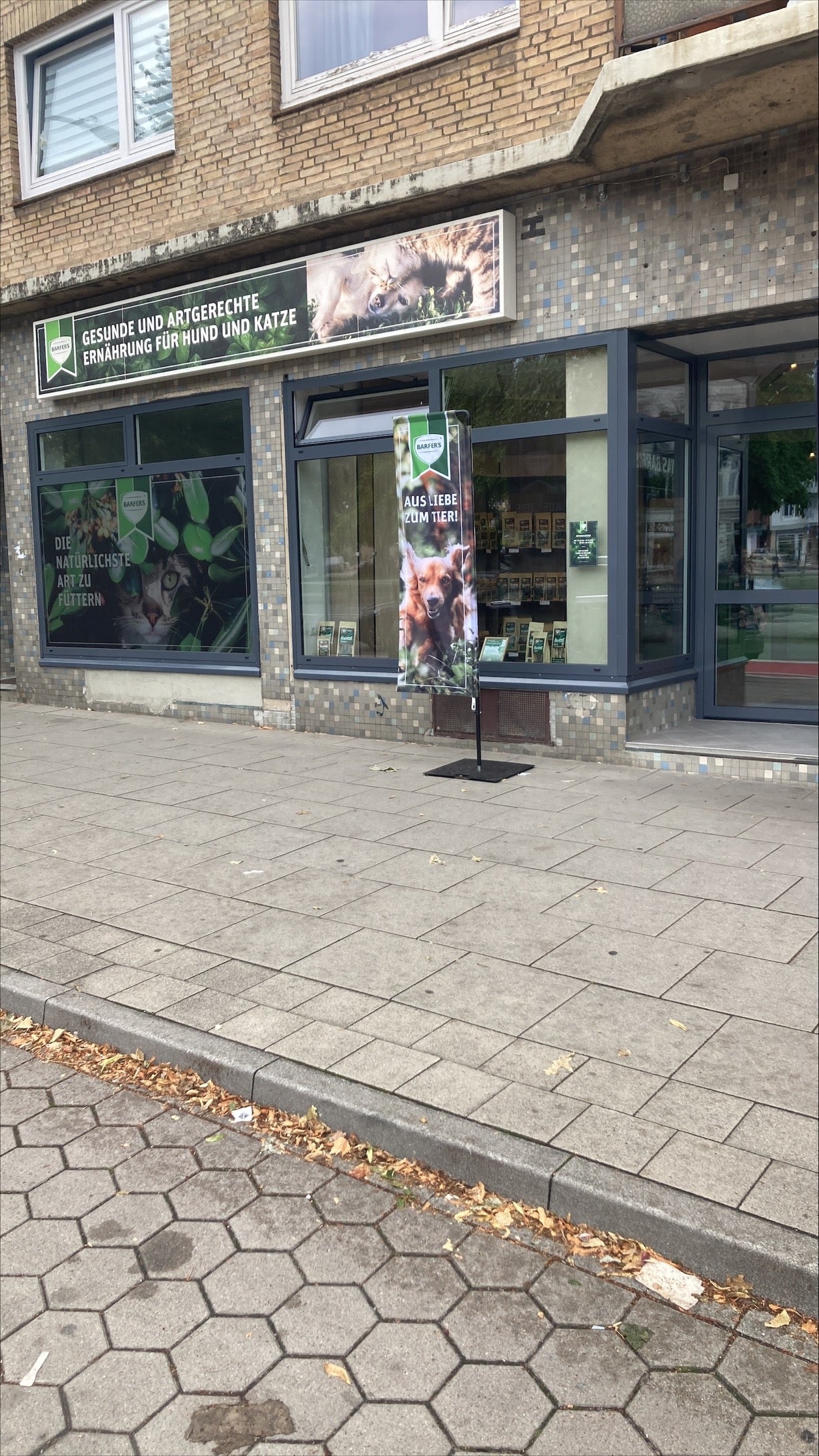 Außenansicht vom BARFER'S Store in Hamburg-Eimsbüttel. Vor dem Store steht eine Werbefahne mit dem Text "AUS LIEBE ZUM TIER!"