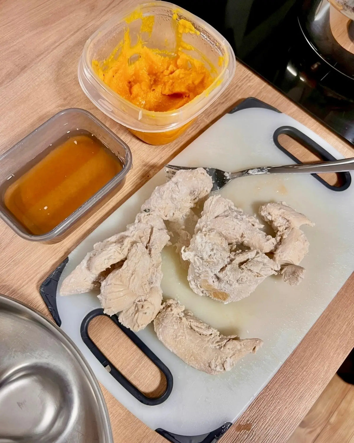 Zerkleinerte, magere Hühnerbrust neben einer Portion pürierter Möhrensuppe und einer Schale mit püriertem Kürbis, vorbereitet als Schonkost für einen Hund mit Durchfall