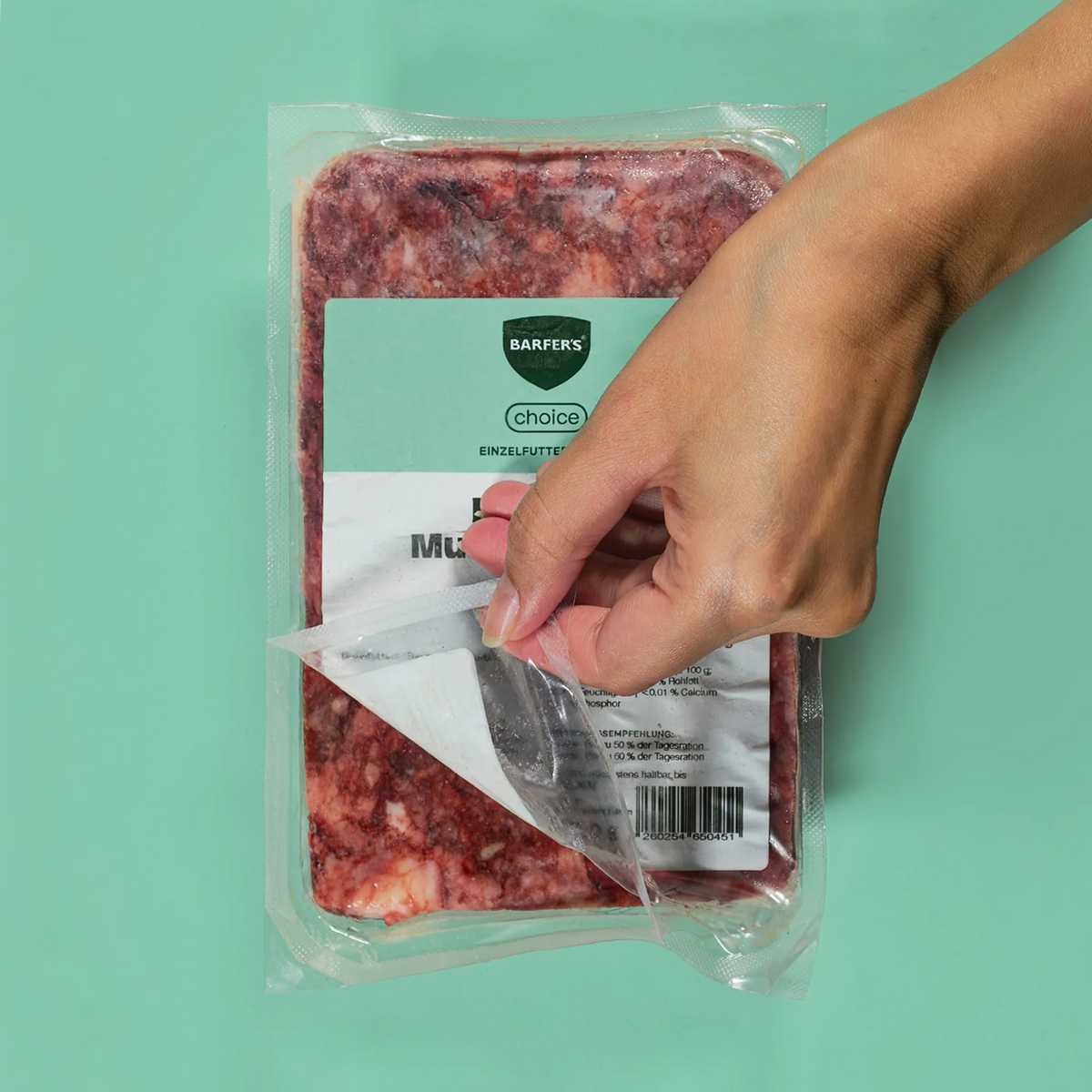 Hand öffnet eine 500-g-Vakuumpackung BARFERS Choice