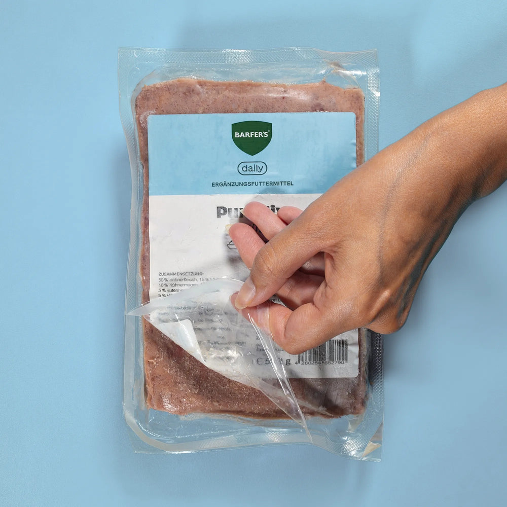 Hand öffnet eine 500-g-Vakuumpackung BARFERS Daily
